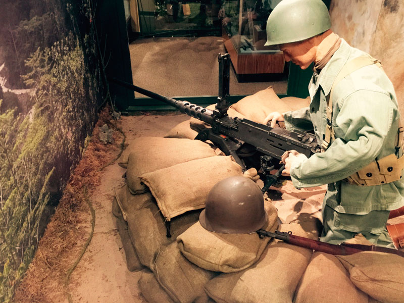 A mannequin Soldier kneeling and holding a machine gun as part of an exhibit at the Lewis Army Museum.